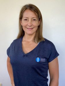 Marcia Orellana, Remedial Massage Therapist at Realign Physio & Co, wearing a navy shirt with logo, smiling in a professional setting.