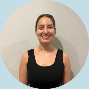 Caroline Leitao, Pilates instructor and movement educator, smiling in a black tank top against a neutral background, promoting fitness and wellness.